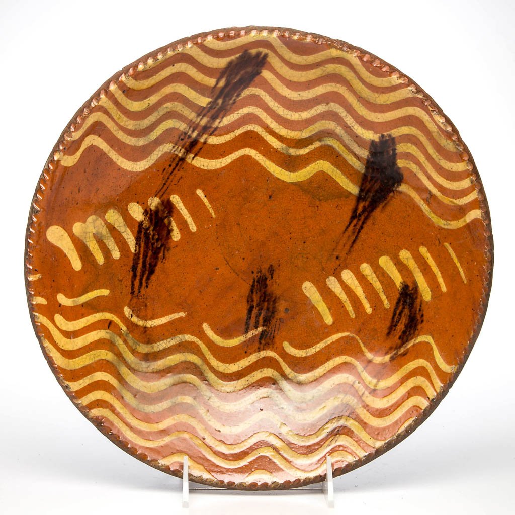 PENNSYLVANIA SLIP-DECORATED EARTHENWARE / REDWARE: PENNSYLVANIA SLIP-DECORATED EARTHENWARE / REDWARE CHARGER, lead-glazed, shallow form with coggled rim, center with strong yellow-slipped decoration and manganese splotches. Second half 18th century. 2