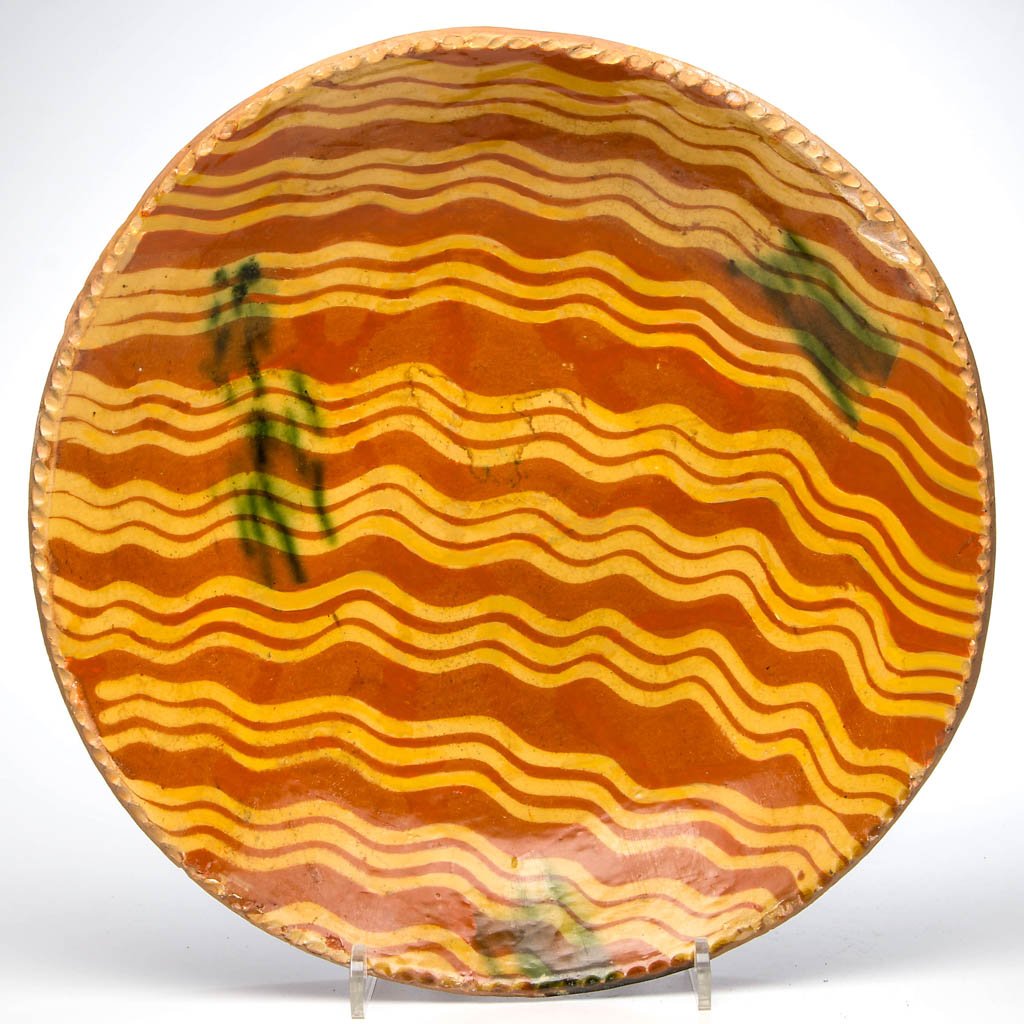 AMERICAN SLIP-DECORATED EARTHENWARE / REDWARE CHARGER: AMERICAN SLIP-DECORATED EARTHENWARE / REDWARE CHARGER, lead-glazed, shallow form with coggled rim, center with strong yellow-slipped decoration and copper splashes. Second half 18th century. 2 3/4" H,