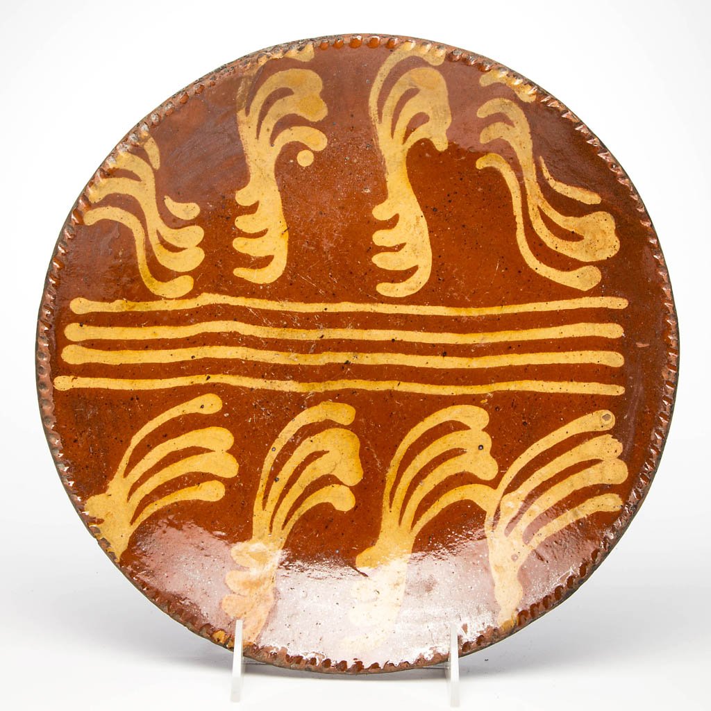 AMERICAN SLIP-DECORATED EARTHENWARE / REDWARE PLATE: AMERICAN SLIP-DECORATED EARTHENWARE / REDWARE PLATE, lead-glazed, shallow form with coggled rim, center with yellow-slipped decoration. 18th or 19th century. 1 3/4" H, 11 1/8" D. Provenance: From a Ne