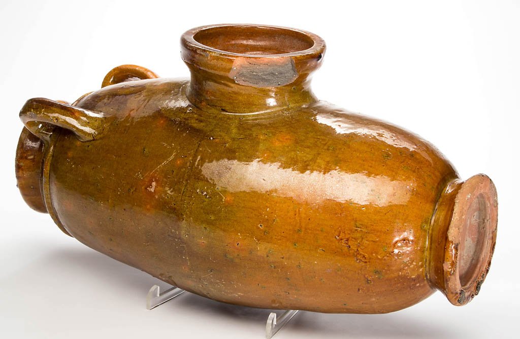 EARTHENWARE / REDWARE STORAGE VESSEL: EARTHENWARE / REDWARE STORAGE VESSEL, lead-glazed, elongated barrel form with a large center opening and two handles at one end. Possibly a salt pig. 19th century. 19 1/2" H.