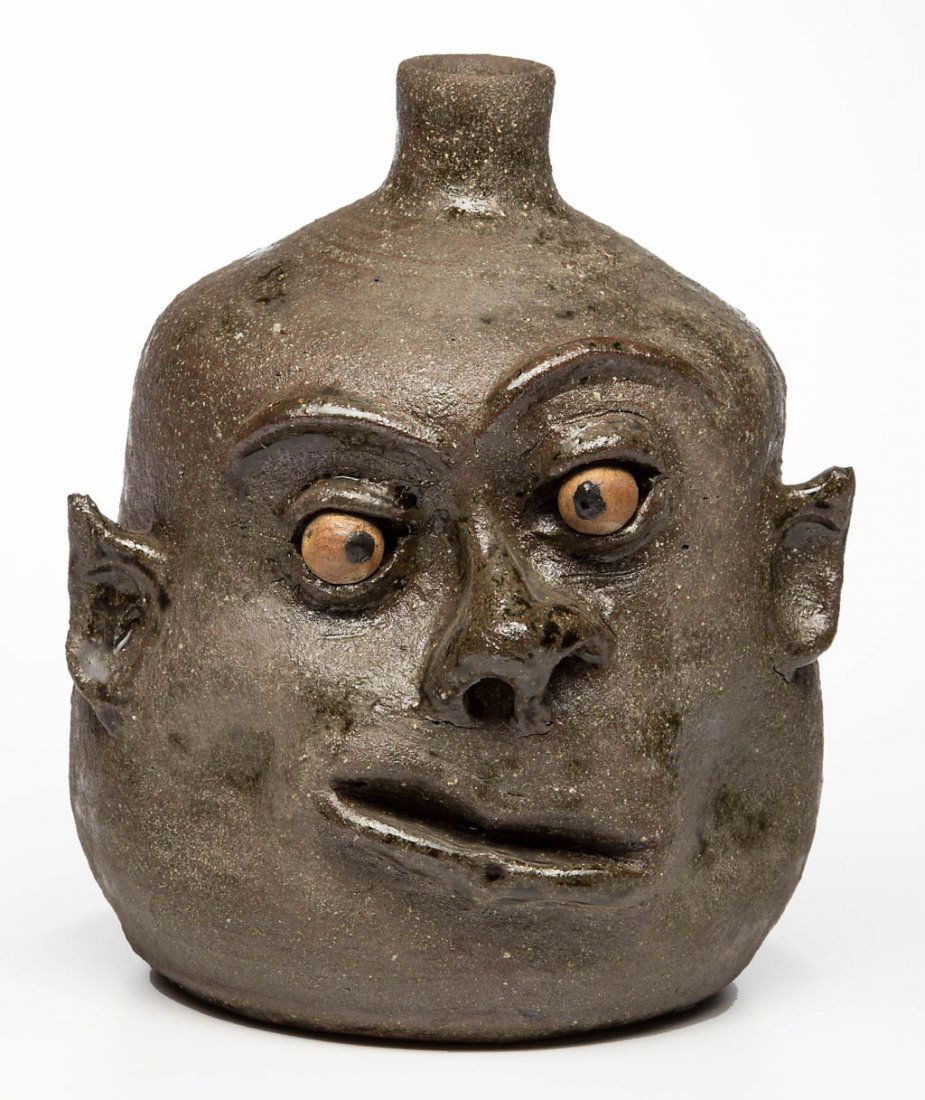 SIGNED "LANIER MEADERS" GEORGIA STONEWARE FACE JUG: SIGNED "LANIER MEADERS" GEORGIA STONEWARE FACE JUG, low-fired matte glaze, inset crooked clay eyes, incised signature to underside. Lanier Meaders (1917-1998), White Co., GA. 20th century. 8 7/8" HOA.