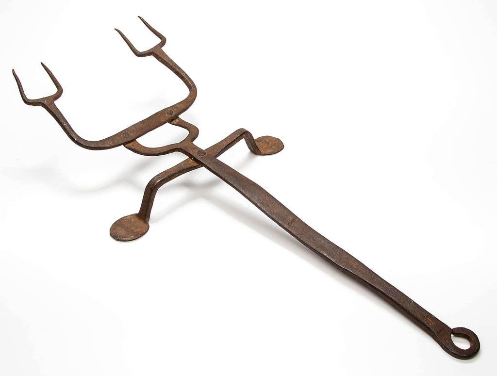WROUGHT-IRON HEARTH BIRD ROASTER / FLESH FORK: WROUGHT-IRON HEARTH BIRD ROASTER / FLESH FORK, central shaft with a small arch which supports a larger arch fitted with a pair of double tines, shaft supported by two simple legs with large penny feet