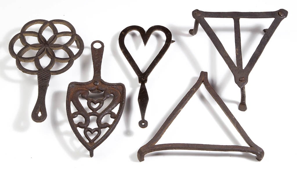WROUGHT-IRON AND CAST-IRON HEARTH TRIVETS, LOT OF FIVE: WROUGHT-IRON AND CAST-IRON HEARTH TRIVETS, LOT OF FIVE, comprising two triangular-form examples, and three handled examples including a single heart-form example, a double heart within scrolls example