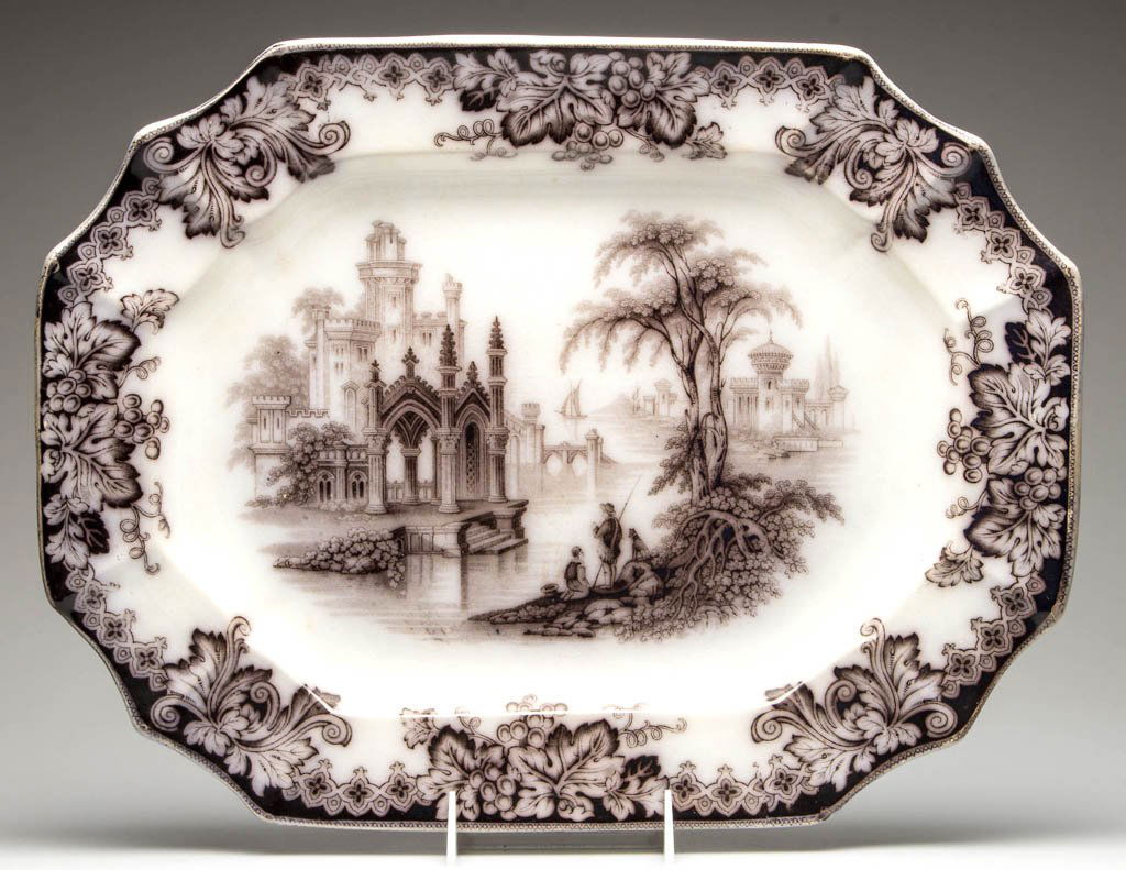 ENGLISH STAFFORDSHIRE J. E. "COBURG" TRANSFERWARE: ENGLISH STAFFORDSHIRE J. E. "COBURG" TRANSFERWARE PLATTER, black/mulberry, gothic buildings within a stream of water with fishermen by a tree, grapevine border, reverse with black stamp mark "COBURG /