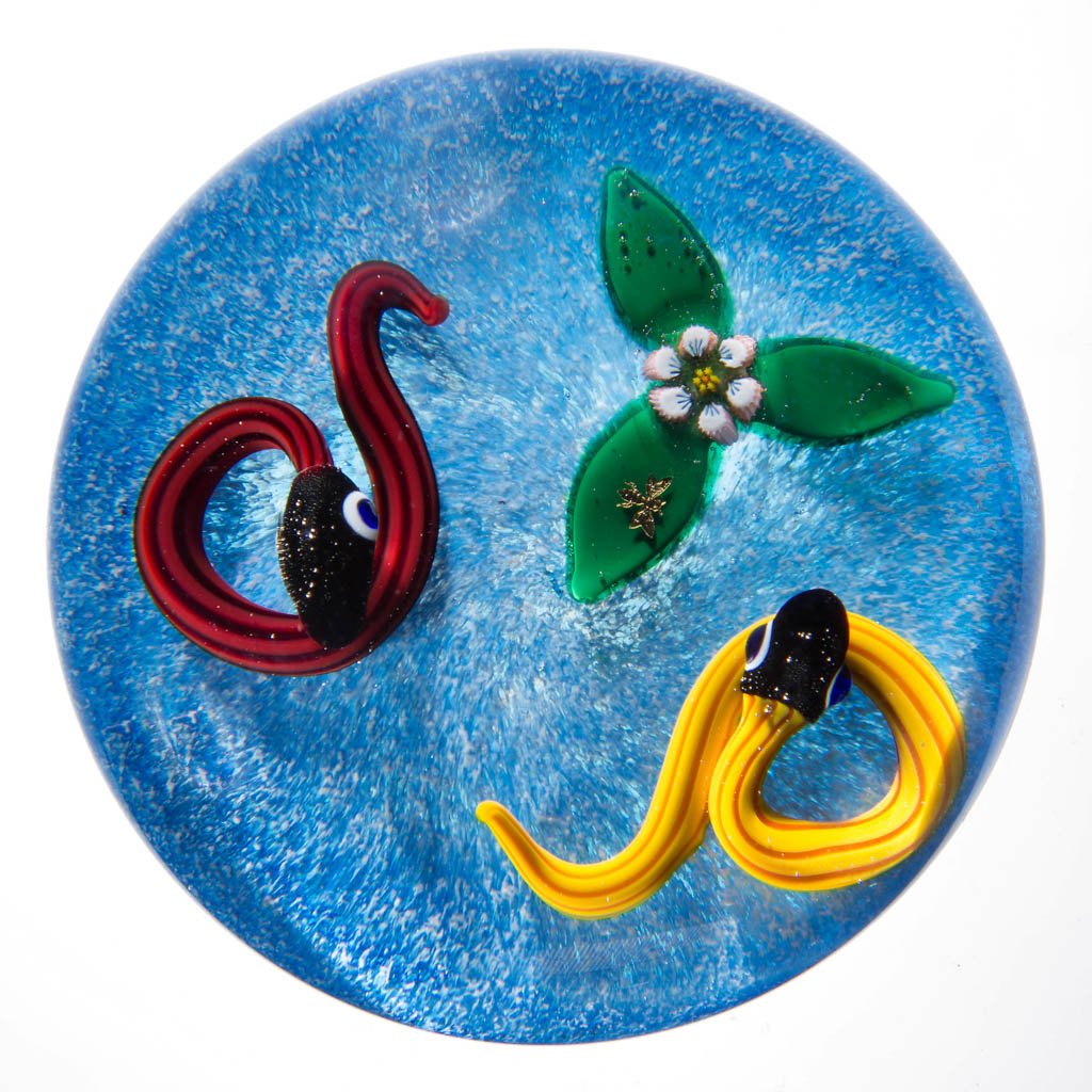 CHARLES KAZIUN STUDIO ART GLASS LAMPWORK PAPERWEIGHT: CHARLES KAZIUN STUDIO ART GLASS LAMPWORK PAPERWEIGHT, depicting yellow and red snakes with a lampwork and millefiori flower and a white and blue background, gold "K" signature on the underside of the 
