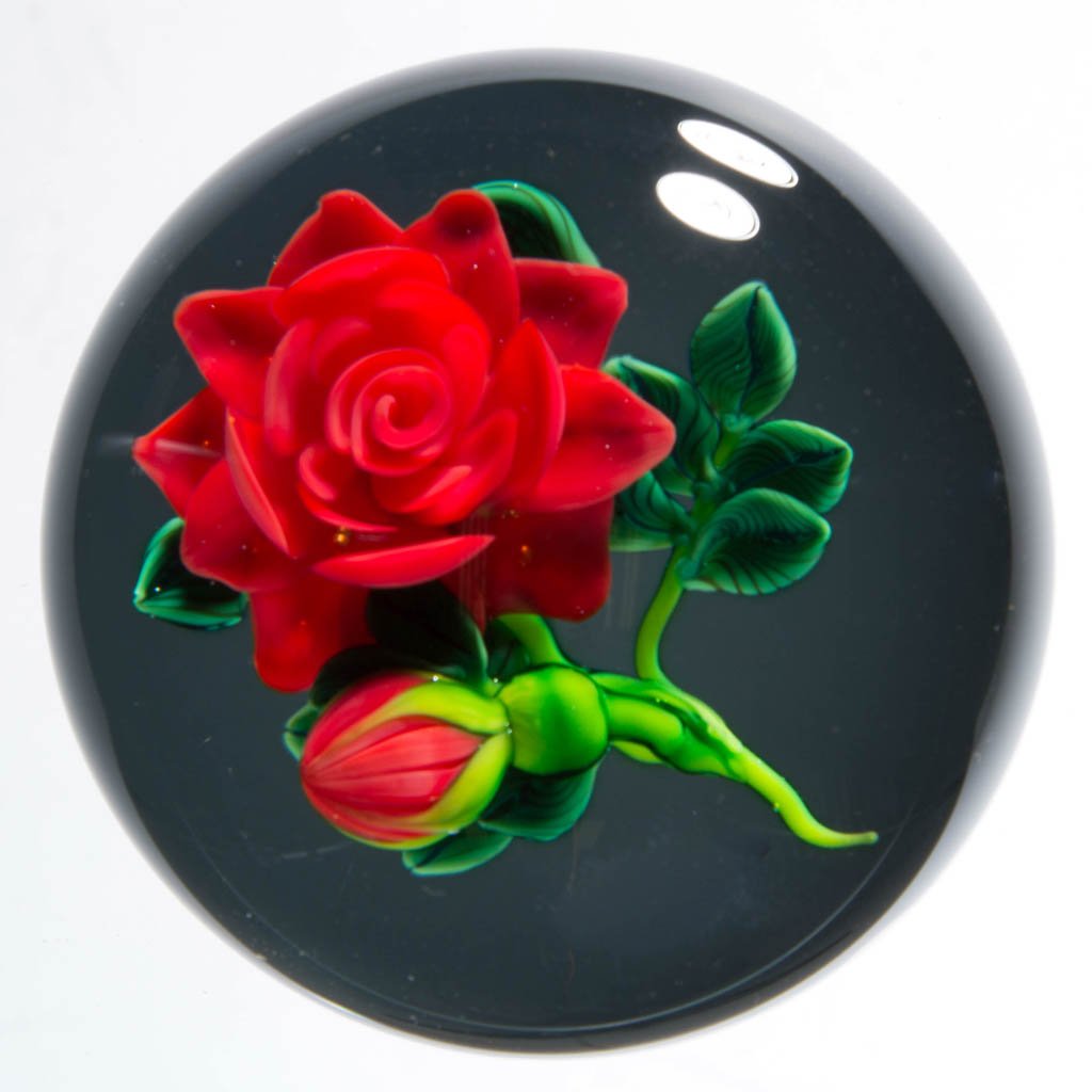 KEN ROSENFELD STUDIO ART GLASS LAMPWORK PAPERWEIGHT: KEN ROSENFELD STUDIO ART GLASS LAMPWORK PAPERWEIGHT, depicting a rose on a greenish black pedestal, signed and dated, signature "R" cane visible. 2000. 2 1/2" D. Provenance: From a private collection.