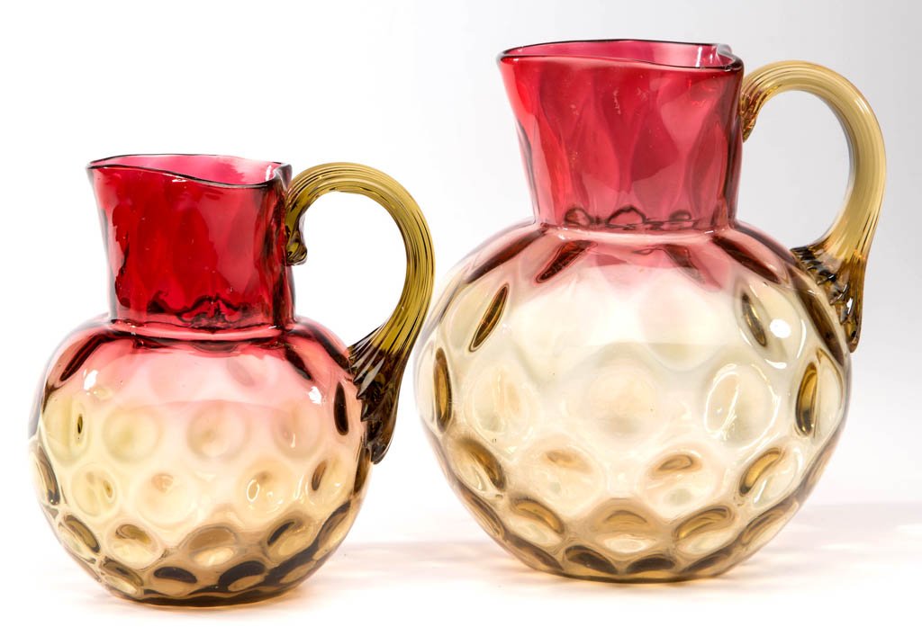 PHOENIX AMBERINA INVERTED THUMBPRINT / SPOT-OPTIC: PHOENIX AMBERINA INVERTED THUMBPRINT / SPOT-OPTIC PITCHERS, LOT OF TWO, each ball shape with a triangular rim, amber applied reeded handle, and polished pontil mark. Phoenix Art Glass. Fourth quarter