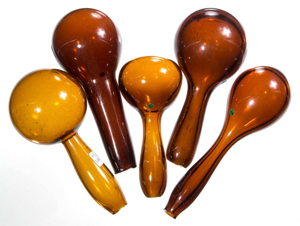 FREE-BLOWN GLASS DARNING BALLS, LOT OF FIVE: FREE-BLOWN GLASS DARNING BALLS, LOT OF FIVE, amber, each handle with rough open-pontil end. 19th century. 5 1/2" to 6 7/8" L. Published: Muller - Darn It! The History and Romance of Darners, pp. 132-1