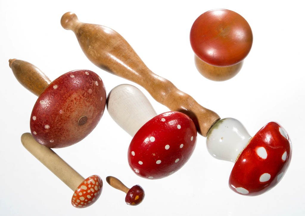 ASSORTED MUSHROOM FORM DARNERS, LOT OF SIX: ASSORTED MUSHROOM FORM DARNERS, LOT OF SIX, wood, porcelain, or celluloid, comprising a scarce celluloid example with screw-on cap and needle case glove darner handle, a porcelain mushroom on wooden h