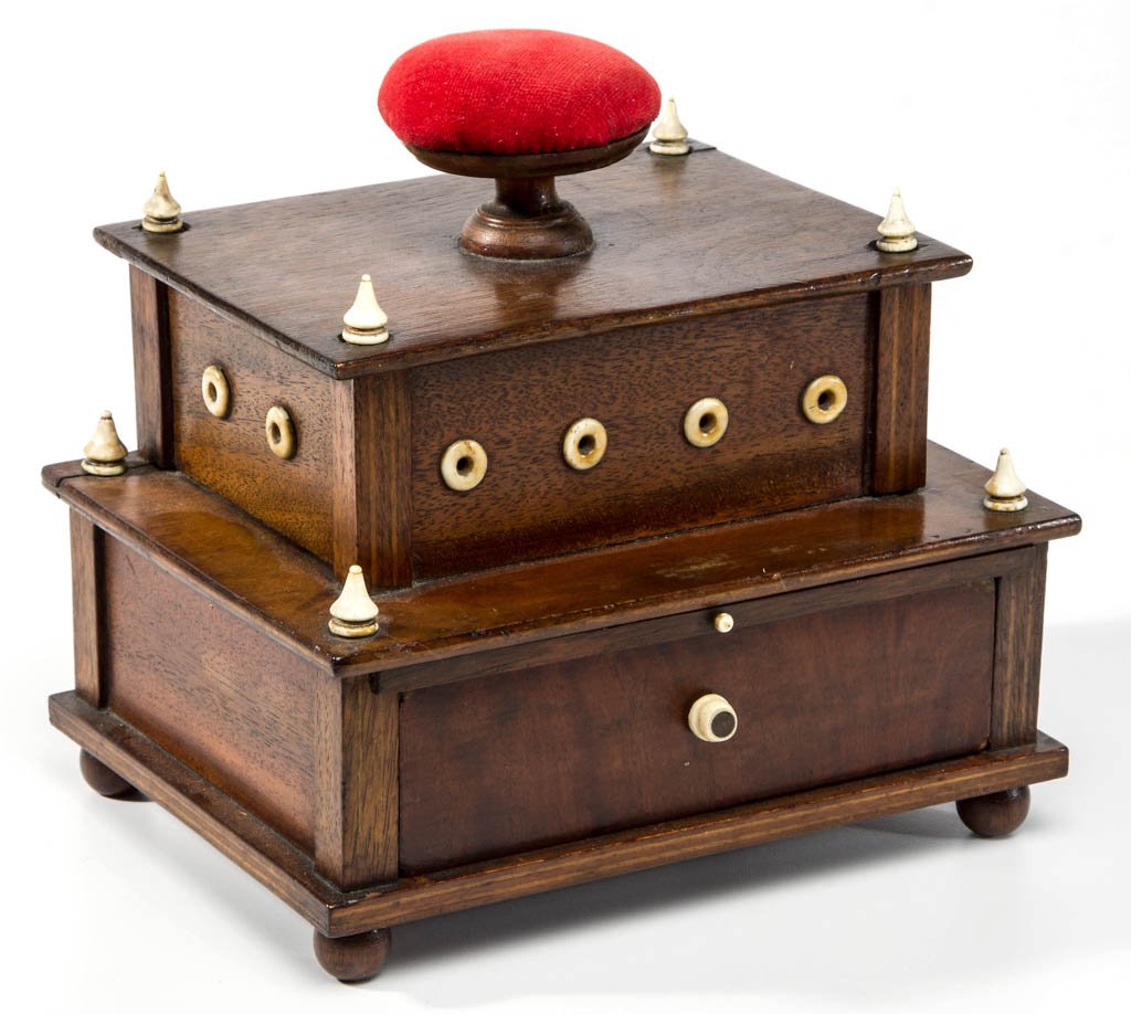 WALNUT ONE-DRAWER SEWING WORK BOX WITH THREAD: WALNUT ONE-DRAWER SEWING WORK BOX WITH THREAD DISPENSERS, two tier, each corner having a bone finial, the red velvet covered pin cushion top which lifts off to reveal seven metal spool reels, ends and