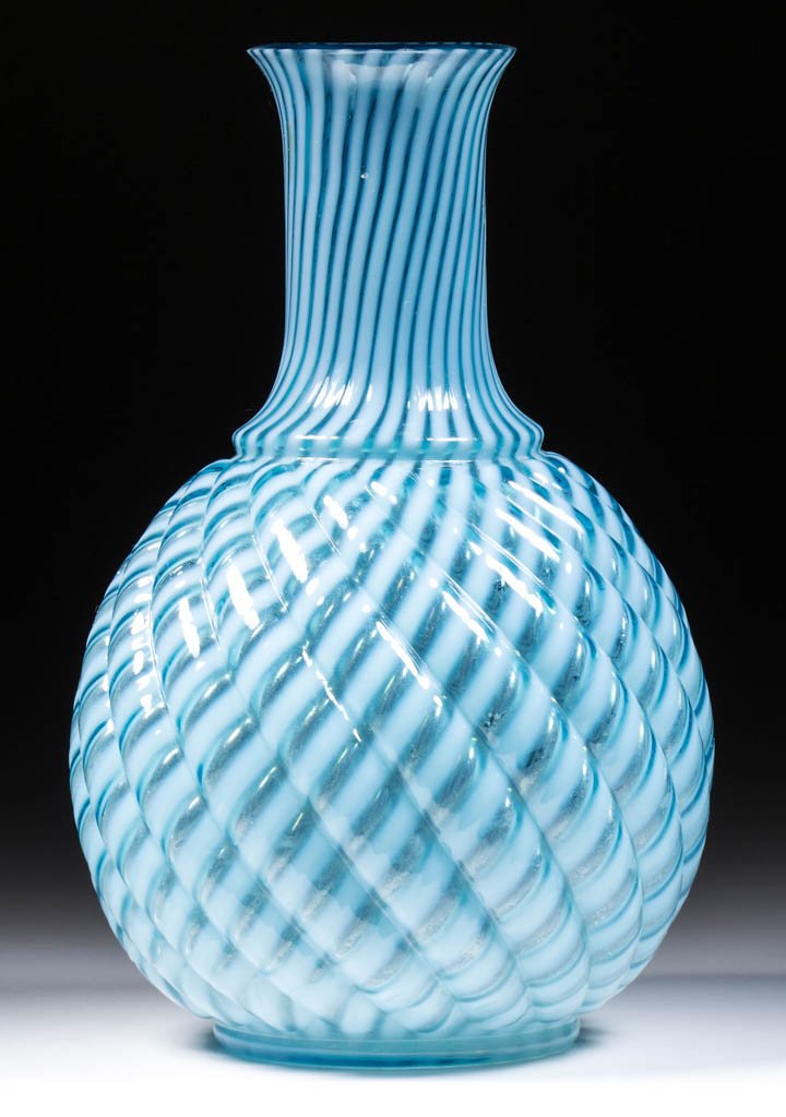REVERSE SWIRL WATER BOTTLE: REVERSE SWIRL WATER BOTTLE, blue opalescent, factory polished rim. Maker unverified. Circa 1888-1902. 8 1/4" H. Literature: Heacock/Elmore - Opalescent Glass From A-Z, p. 96, center. Provenance: From