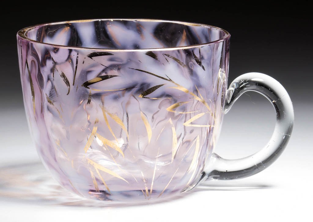 SCOTTISH MOOR PUNCH CUP: SCOTTISH MOOR PUNCH CUP, amethyst opalescent with gilt decoration outlining pattern, applied colorless handle, factory polished rim. Circa 1890. 2 1/2" H. Literature: Parallels Heacock/Gamble - Victor