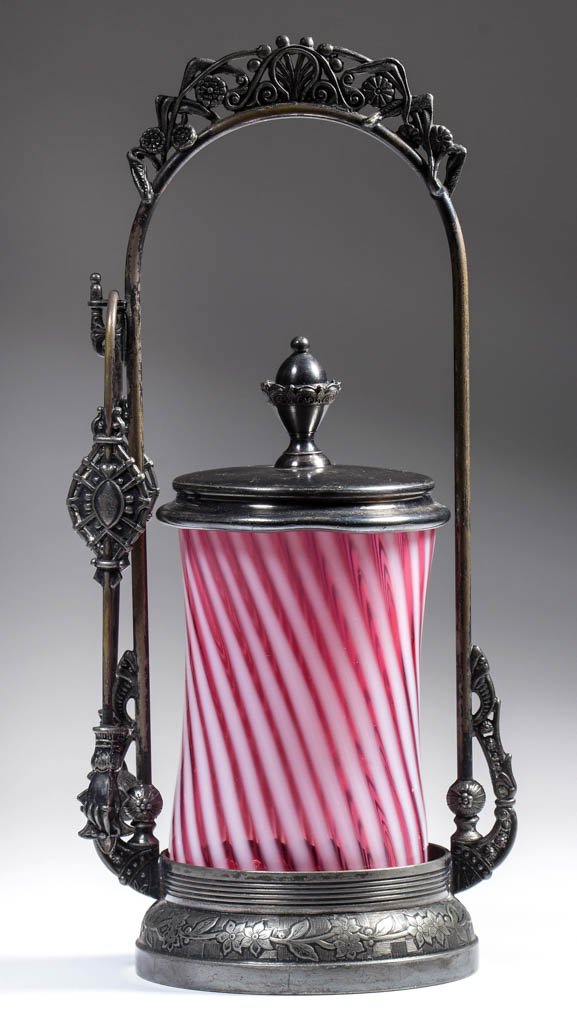 STRIPED RIB-OPTIC PICKLE CASTER: STRIPED RIB-OPTIC PICKLE CASTER, cranberry opalescent, fitted in a Wilcox quadruple-plate stand and numbered "4615," with tongs. Fourth quarter 19th century. 11" HOA, jar 4 5/8" H. Provenance: From th