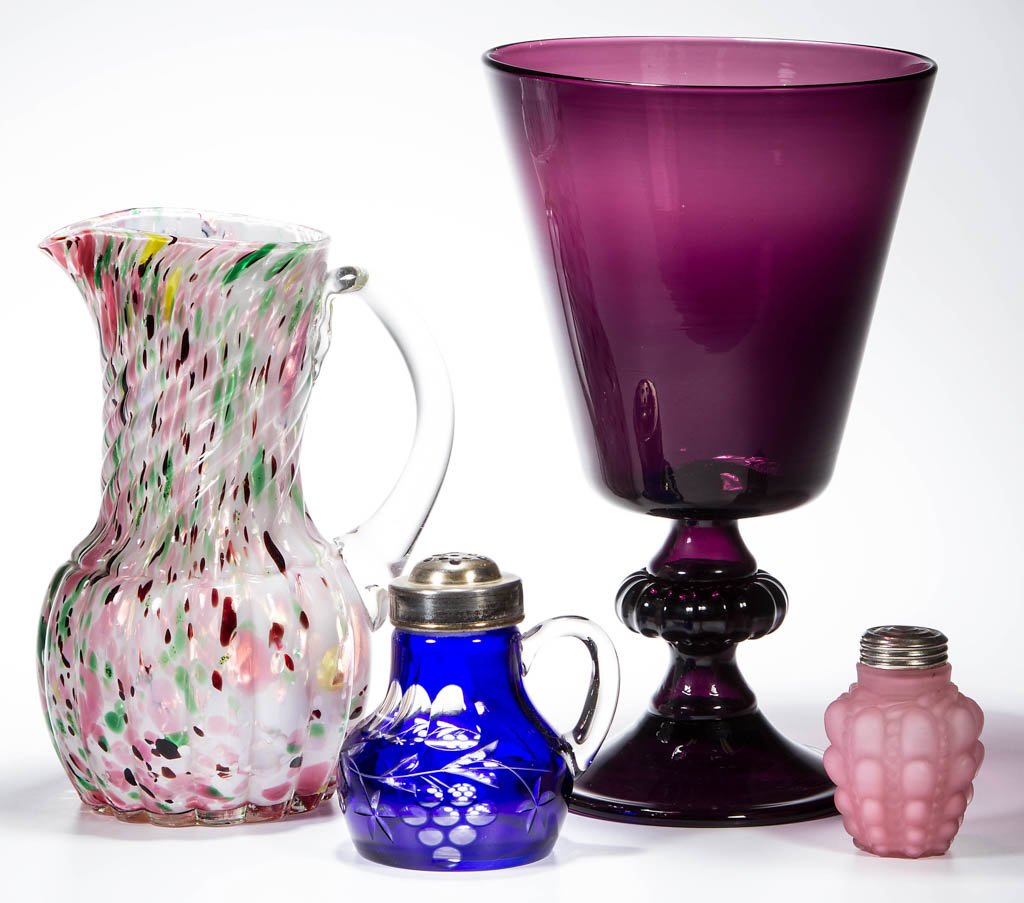 ASSORTED COLORED GLASS ARTICLES, LOT OF FOUR: ASSORTED COLORED GLASS ARTICLES, LOT OF FOUR, including a spatter/spangle water pitcher, a cut overlay handled sugar shaker, and an amethyst large blown chalice. 20th century. 3 1/4" to 11" H. Provena