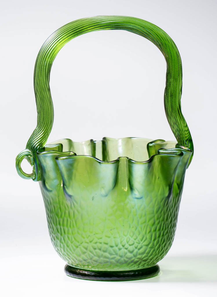 LOETZ MARTELE BASKET: LOETZ MARTELE BASKET, green iridescent, boldly ruffled rim, applied reeded handle with applied curl to one terminal, as made, polished pontil mark. Late 19th century. 7" HOA, 4 3/4" D.