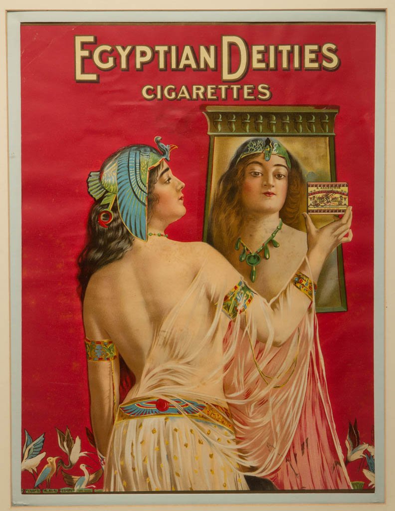 EGYPTIAN DEITIES CIGARETTES PAPER ADVERTISING SIGN: EGYPTIAN DEITIES CIGARETTES PAPER ADVERTISING SIGN, with lithographed imagery featuring a scantily clad woman in ancient Egyptian costume. Copyright 1908 in lower left corner. Matted under glass in a 