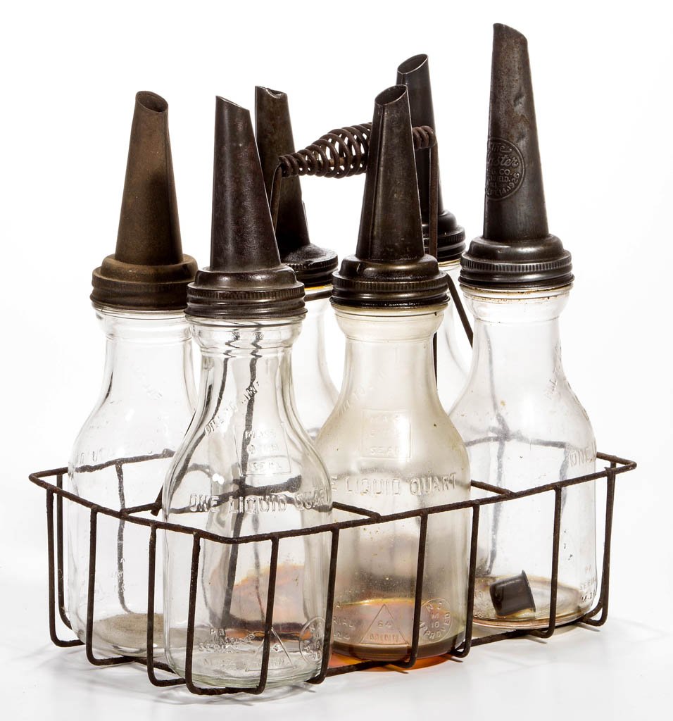 GLASS MOTOR OIL BOTTLES AND CARRIER: GLASS MOTOR OIL BOTTLES AND CARRIER, group of six quart bottles with screw-on metal spouts, in a wire-style carrier with handle. First half 20th century. 15" HOA, 8 1/2" x 13" carrier. Provenance: Pro
