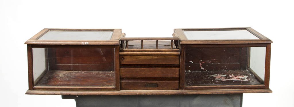 COUNTY STORE OAK COUNTER-TOP SHOWCASE: COUNTY STORE OAK COUNTER-TOP SHOWCASE, central lift-top desk with gallery above a cash drawer, flanked on each side by a showcase with fold-down rear door. Fourth quarter 19th century. 12" H, 53 1/2" 