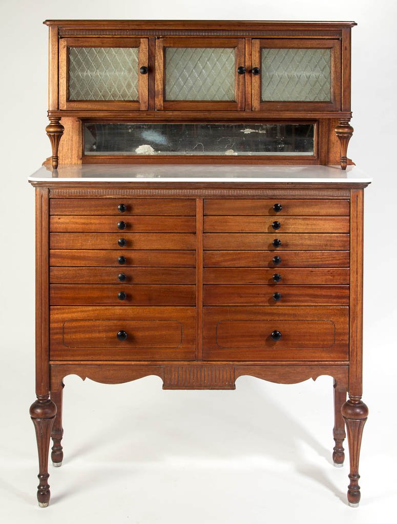 AMERICAN CABINET CO. MAHOGANY DENTAL CABINET: AMERICAN CABINET CO. MAHOGANY DENTAL CABINET, upper cabinet with three hinged textured-glass pane doors, above an opaque-white glass top and two stacks of seven graduated drawers, raised on tall flute