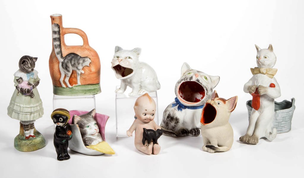GERMAN CHINA NOVELTY CAT FIGURES, LOT OF NINE: GERMAN CHINA NOVELTY CAT FIGURES, LOT OF NINE, mostly bisque, including a Kewpie, three open-mouth ashtrays, a flask, and a nodder marked with a blue anchor under base. Late 19th/first quarter 20th ce