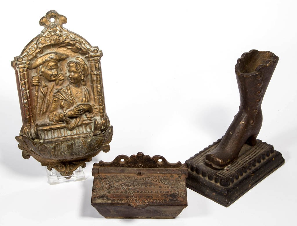ASSORTED FIGURAL CAST-METAL MATCH HOLDERS / SAFES, LOT: ASSORTED FIGURAL CAST-METAL MATCH HOLDERS / SAFES, LOT OF THREE, comprising two wall mount examples, including one of a couple in an ornamental frame and over a single large pocket; a rectangular exam