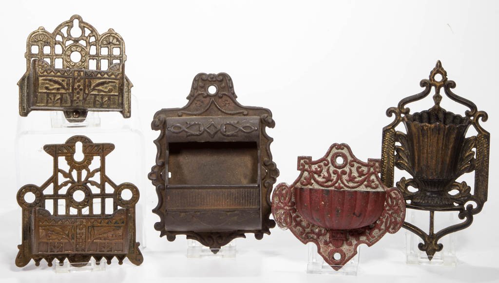 ASSORTED FIGURAL CAST-METAL MATCH HOLDERS / SAFES, LOT: ASSORTED FIGURAL CAST-METAL MATCH HOLDERS / SAFES, LOT OF FIVE, wall mounts, comprising four cast iron and one cast brass example, each with various scroll ornamentation, one example with reverse inci