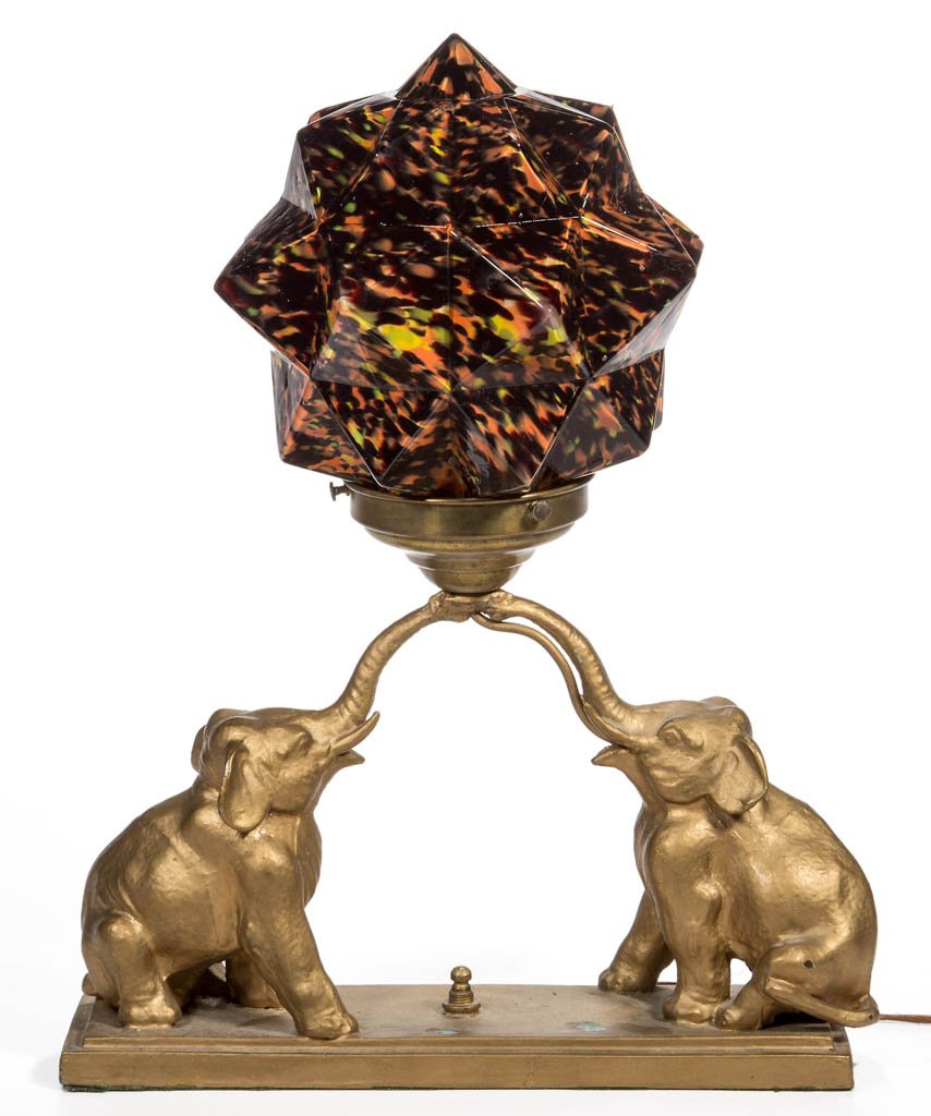 PAINTED METAL DOUBLE ELEPHANT ELECTRIC LAMP: PAINTED METAL DOUBLE ELEPHANT ELECTRIC LAMP, cased glass spatter shade with embossed monogram, possibly J&K, base with later paint. Circa 1920. 15" HOA, 11 1/2" W. Provenance: From the Dorothy R. Dani