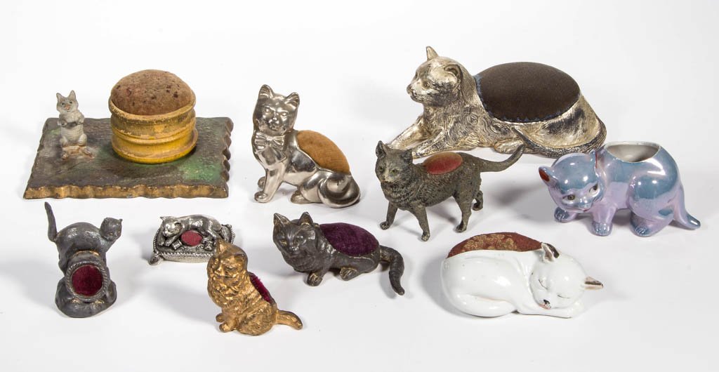 ASSORTED FIGURAL CAT PIN CUSHIONS, LOT OF TEN: ASSORTED FIGURAL CAT PIN CUSHIONS, LOT OF TEN, including two cold-painted metal, other metal, and German and Japanese china. 20th century. 1" to 3" H. Provenance: From the Dorothy R. Daniel estate, Ar