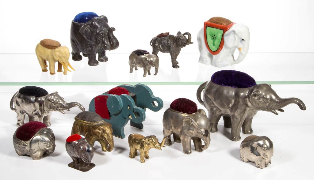 ASSORTED FIGURAL ELEPHANT PIN CUSHIONS, LOT OF 14: ASSORTED FIGURAL ELEPHANT PIN CUSHIONS, LOT OF 14, including one sterling silver, assorted other metals, painted wood, china, and celluloid, markings include Germany and Japan. 20th century. 1 1/2" to