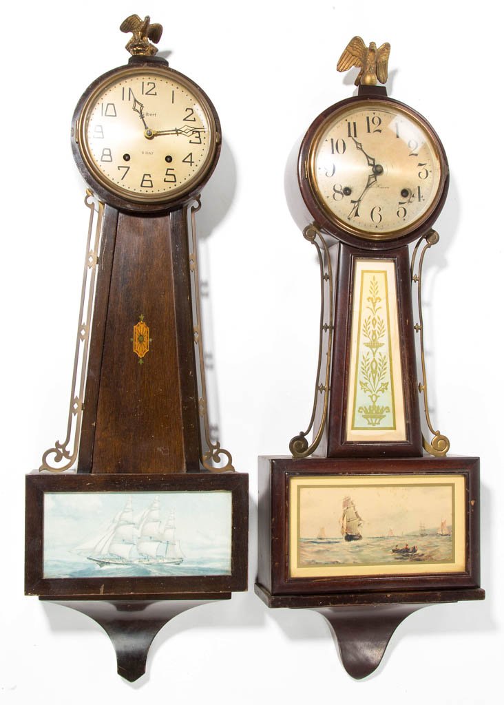 AMERICAN BANJO-STYLE WALL CLOCKS, LOT OF TWO: AMERICAN BANJO-STYLE WALL CLOCKS, LOT OF TWO, New Haven and Gilbert, each with eagle finial, nautical-theme tablet, pendulum, and key. First half 20th century. 29" and 30" HOA. Provenance: From a Page