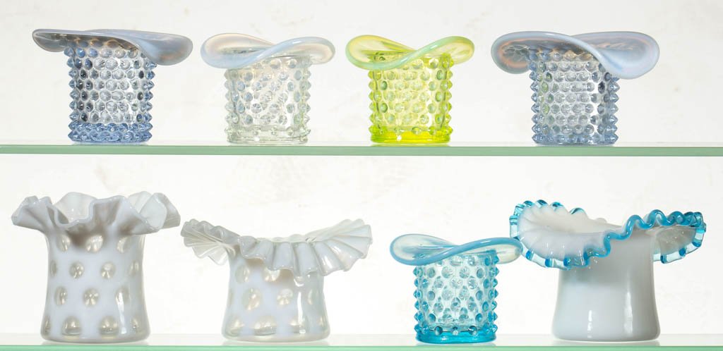 ASSORTED FENTON NOVELTY HAT TOOTHPICK HOLDERS, LOT OF: ASSORTED FENTON NOVELTY HAT TOOTHPICK HOLDERS, LOT OF EIGHT, colorless, blue, and vaseline (uranium), including three examples with ruffled rims. Fenton Art Glass. 20th century. 2 1/2" to 3 1/2" H. Pr