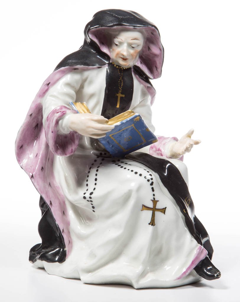 ENGLISH BOW PORCELAIN FIGURE OF A SEATED NUN: ENGLISH BOW PORCELAIN FIGURE OF A SEATED NUN, modeled with studious pose, holding a Bible in one hand, reading "Ave Maria" and the other hand outstretched, her hooded cloak over her robes, one black-s