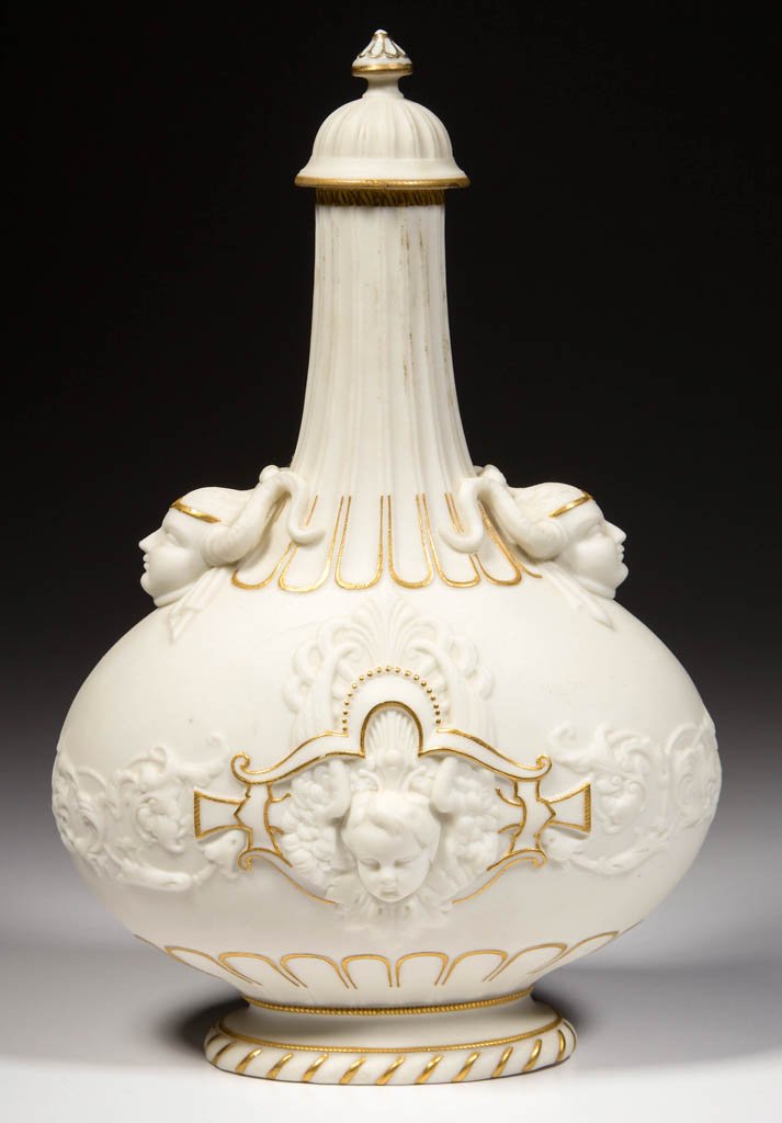 ENGLISH PARIAN PORCELAIN MASK-MOLDED BOTTLE AND COVER: ENGLISH PARIAN PORCELAIN MASK-MOLDED BOTTLE AND COVER, of squat body and elongated neck, with high-domed cover topped by a pointed knop, molded with neo-Renaissance masks, scrolls, putti heads, foliat