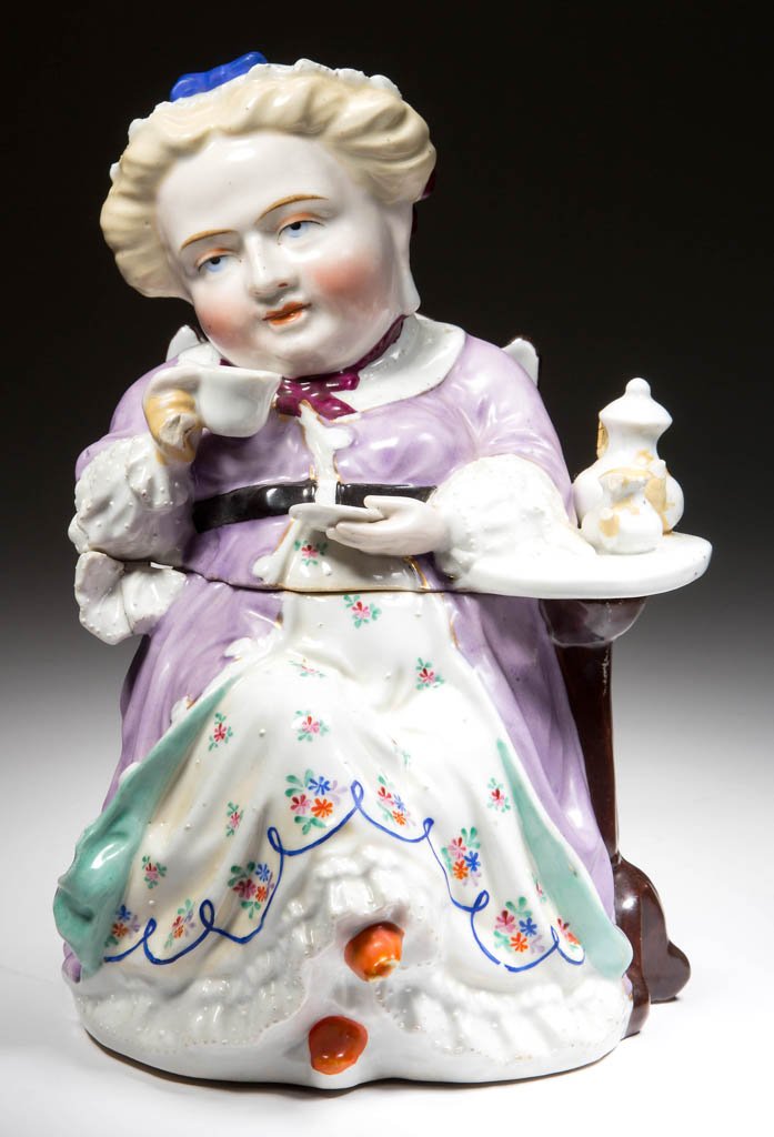 CONTINENTAL PORCELAIN FIGURAL TOBY-TYPE TEA CADDY OR: CONTINENTAL PORCELAIN FIGURAL TOBY-TYPE TEA CADDY OR SUGAR BOX, modeled as a seated Victorian lady, drinking tea near a table holding the teapot and cream jug, split at the waist to form a box, the de