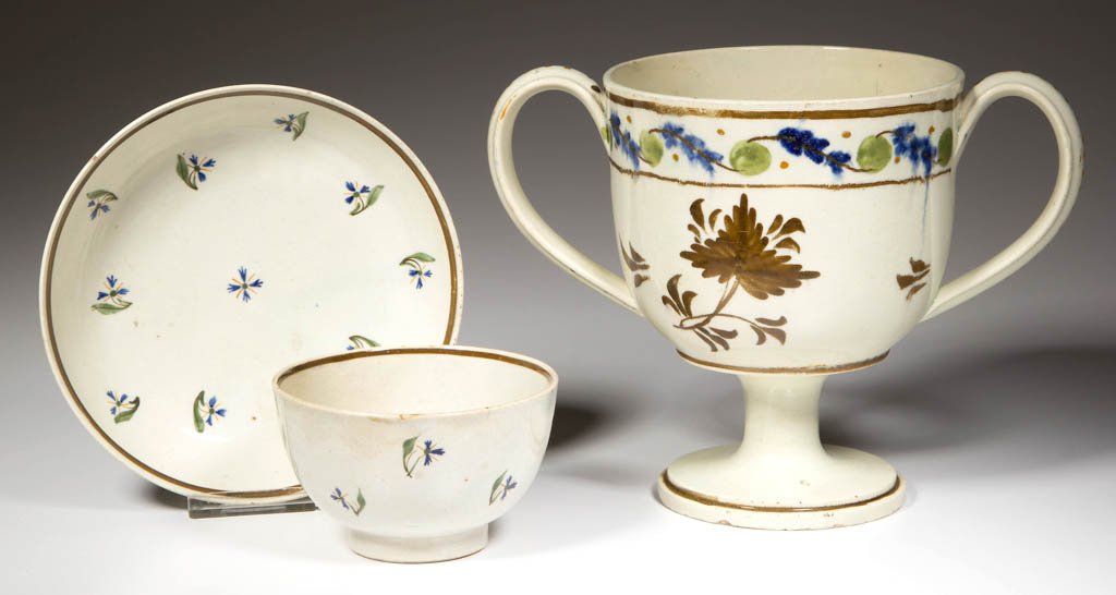 ENGLISH STAFFORDSHIRE POTTERY PEARLWARE DRINKING: ENGLISH STAFFORDSHIRE POTTERY PEARLWARE DRINKING ARTICLES, LOT OF THREE, comprising a two-handled loving cup on pedestal foot, and a tea bowl and saucer, both painted with floral and foliate motifs, t