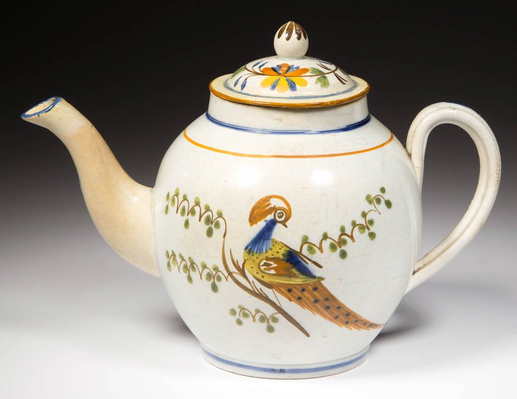 ENGLISH STAFFORDSHIRE POTTERY PEARLWARE PEAFOWL TEAPOT: ENGLISH STAFFORDSHIRE POTTERY PEARLWARE PEAFOWL TEAPOT AND COVER, the ovoid teapot with ribbed strap handle and curving spout, the lightly-domed cover with tall, globular knop; painted to both sides w