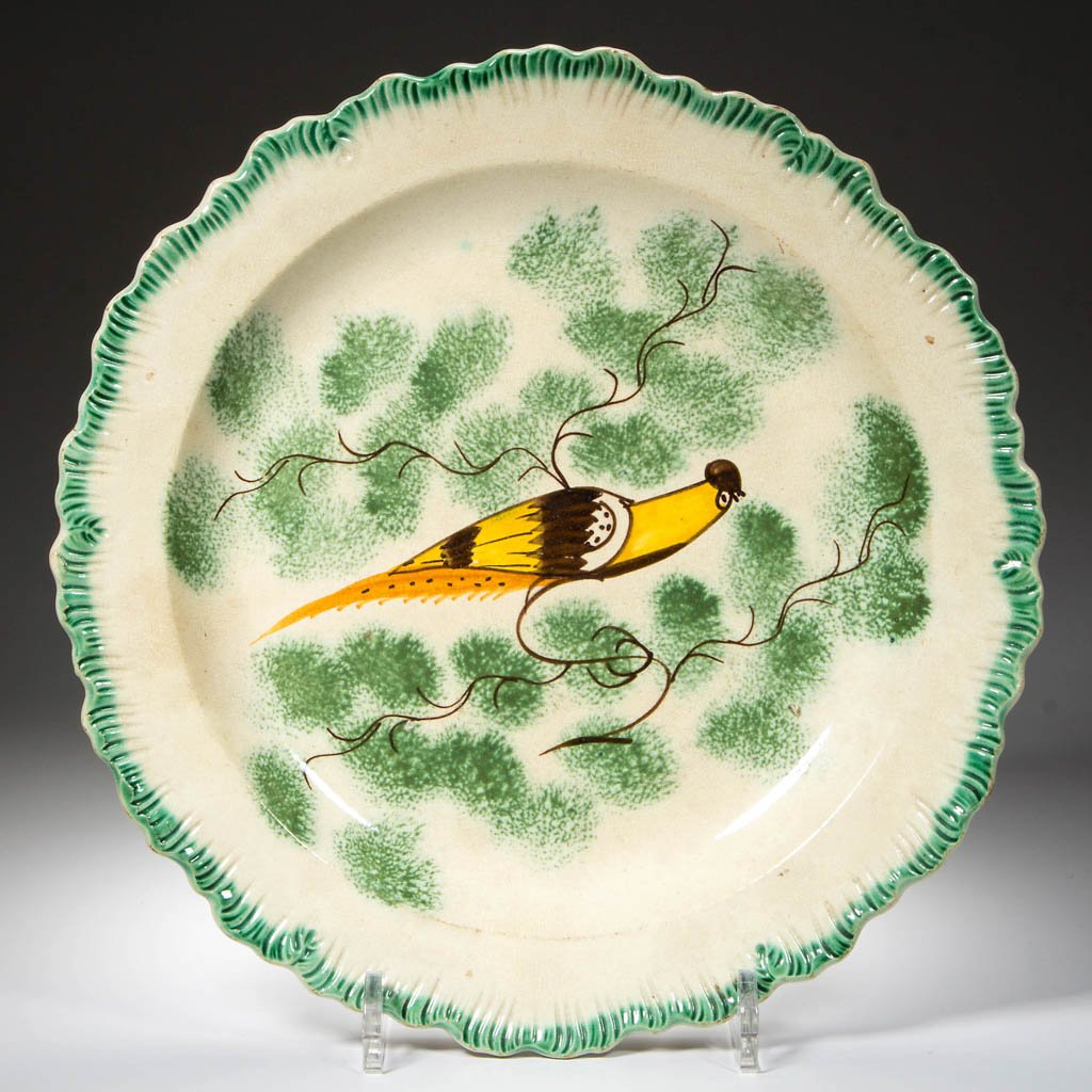 ENGLISH STAFFORDSHIRE POTTERY PEARLWARE PEAFOWL PLATE: ENGLISH STAFFORDSHIRE POTTERY PEARLWARE PEAFOWL PLATE, with press-molded scallop-shell rim, painted with a green band to edge, centering a long-tailed peafowl painted in ocher, orange and brown, stand