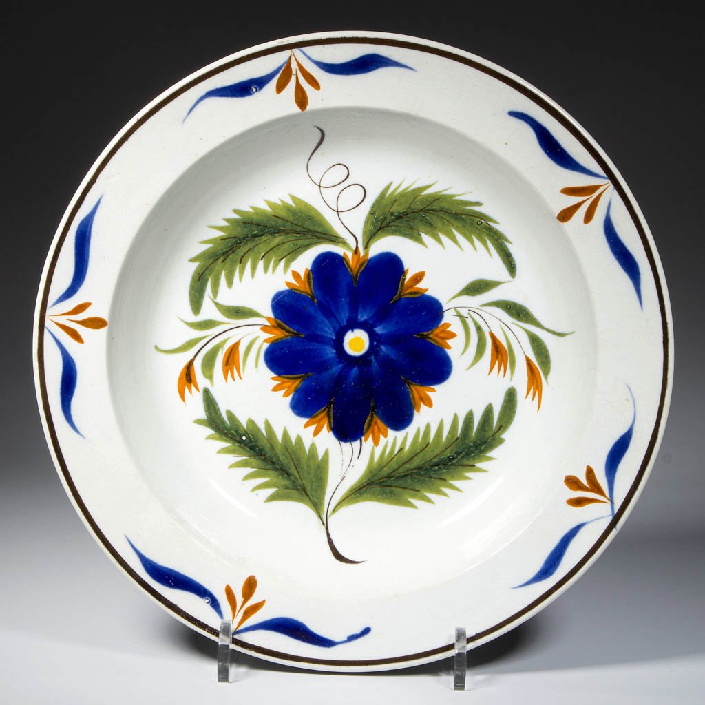 ENGLISH STAFFORDSHIRE POTTERY PEARLWARE FLORAL RIM SOUP: ENGLISH STAFFORDSHIRE POTTERY PEARLWARE FLORAL RIM SOUP PLATE, of press-molded form, with plain rim, enameled with a brown band to the rim, with blue and red foliate motifs to shoulder, the face paint