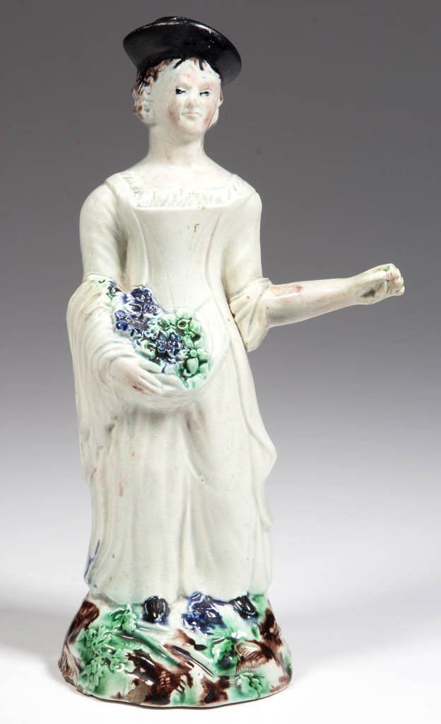ENGLISH STAFFORDSHIRE POTTERY PEARLWARE FIGURE OF A: ENGLISH STAFFORDSHIRE POTTERY PEARLWARE FIGURE OF A FLOWER SELLER, modeled as a young woman wearing a hat, holding a cluster of blooms in her right hand, her left arm extended to display a (now absent