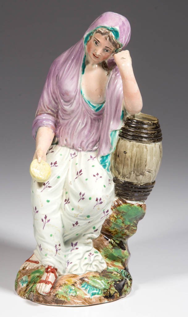 ENGLISH STAFFORDSHIRE POTTERY "MOURNING WIDOW" FIGURE: ENGLISH STAFFORDSHIRE POTTERY "MOURNING WIDOW" FIGURE, seated on a rocky mound base, her head leaning on her left arm, perched on a barrel, her right hand holding a sponge or muffin. Unmarked. Circa 1