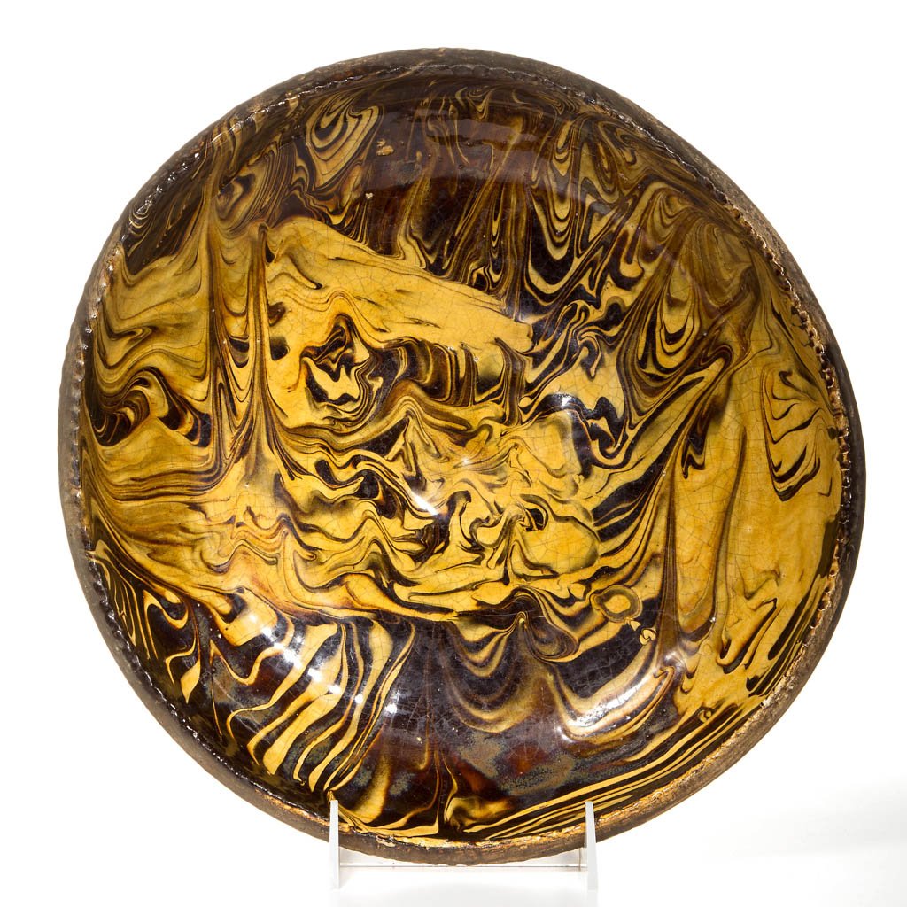 ENGLISH STAFFORDSHIRE POTTERY SLIP-DECORATED: ENGLISH STAFFORDSHIRE POTTERY SLIP-DECORATED EARTHENWARE OR REDWARE BOWL, of shallow form with a pinched rim, decorated with manganese and lead slip in marbleized patterns all over the surface, the un