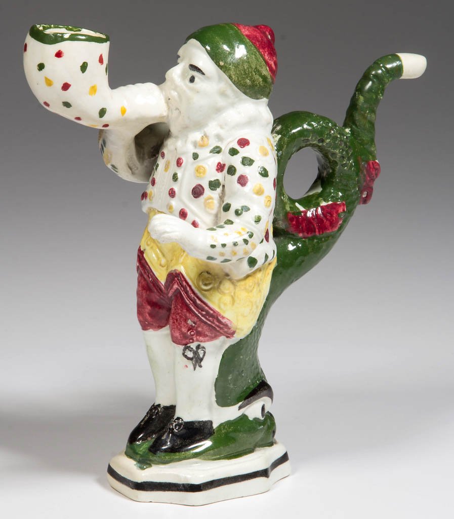 ENGLISH YORKSHIRE OR SCOTTISH POTTERY PEARLWARE FIGURAL: ENGLISH YORKSHIRE OR SCOTTISH POTTERY PEARLWARE FIGURAL PIPE, formed as a standing man blowing a pipe, holding the stem of the oversized bowl, leaning back on a semi-formed dolphin whose curling tail