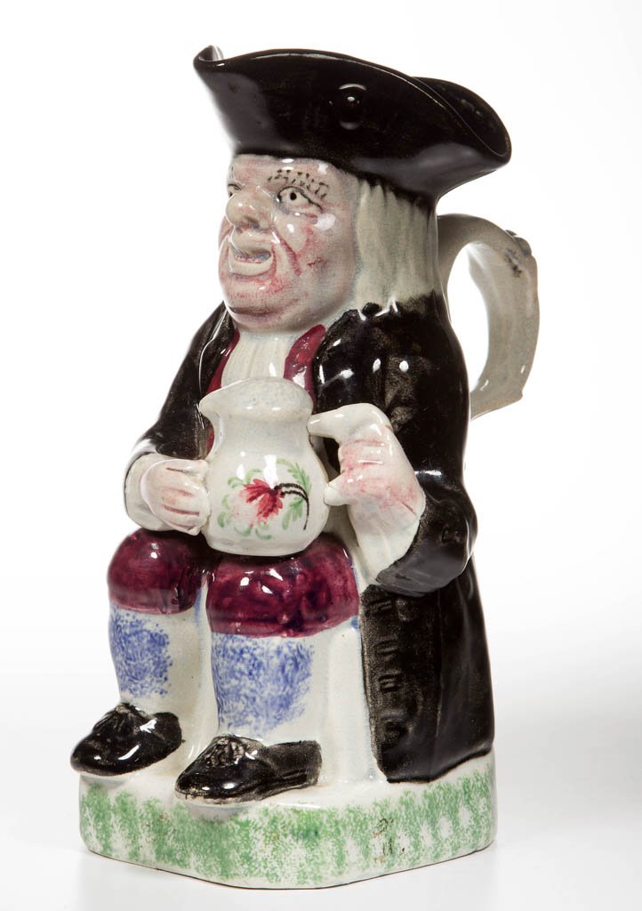 ENGLISH YORKSHIRE-TYPE POTTERY PEARLWARE PURPLE-FACE: ENGLISH YORKSHIRE-TYPE POTTERY PEARLWARE PURPLE-FACE TOBY PITCHER, the toper seated under his hat and quaffing his ale out of a large jug, on a canted-corner rectangular base, painted with black, red-