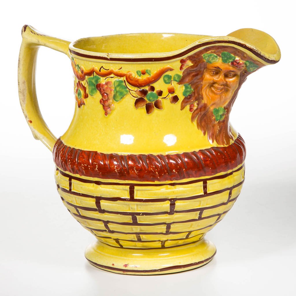 ENGLISH STAFFORDSHIRE POTTERY PEARLWARE CANARY YELLOW: ENGLISH STAFFORDSHIRE POTTERY PEARLWARE CANARY YELLOW BACCHUS MASK PITCHER, of baluster form with tau-shaped handle, the spout molded with two Bacchic masks, a band of flowering and fruiting grapevine