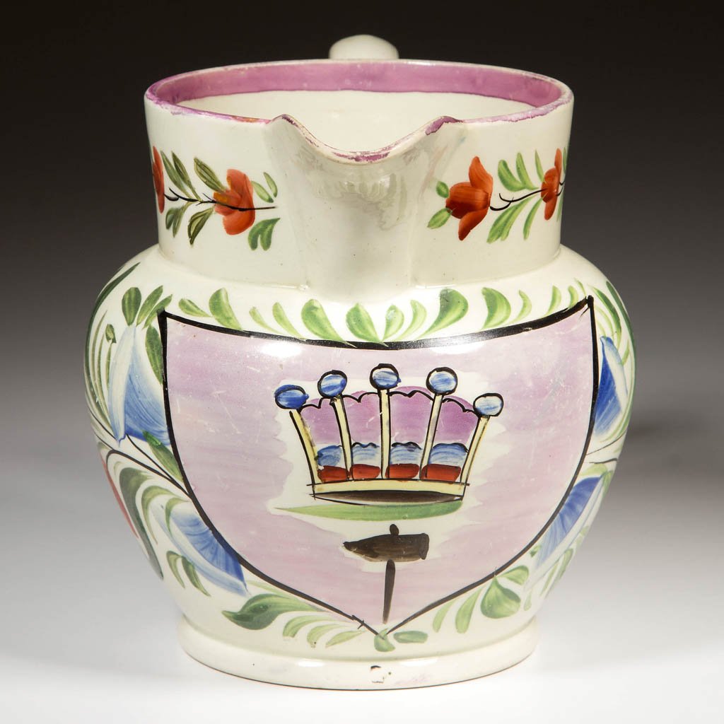 ENGLISH STAFFORDSHIRE POTTERY PEARLWARE PINK LUSTERWARE: ENGLISH STAFFORDSHIRE POTTERY PEARLWARE PINK LUSTERWARE PSEUDO-ARMORIAL PITCHER, of Dutch shape, with a lateral band of flowers painted to the neck, and a crown reserved on the lusterware ground, surr