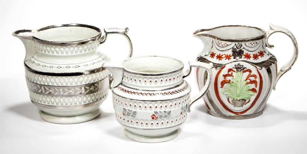 ENGLISH STAFFORDSHIRE POTTERY PEARLWARE MOLDED AND: ENGLISH STAFFORDSHIRE POTTERY PEARLWARE MOLDED AND LUSTERED PITCHERS, LOT OF THREE, comprising an ovular jug with C-scroll handle and shell-molded spout, molded to the sides with garlands and stars ov
