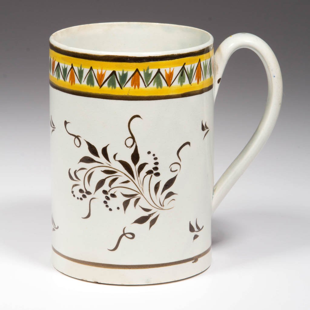 ENGLISH STAFFORDSHIRE POTTERY PEARLWARE PRATTWARE-HUED: ENGLISH STAFFORDSHIRE POTTERY PEARLWARE PRATTWARE-HUED MUG, of slightly-flaring, cylindrical-sided form, with wide and simple handle, painted in Prattware hues with a band of stylized leaves in brown,
