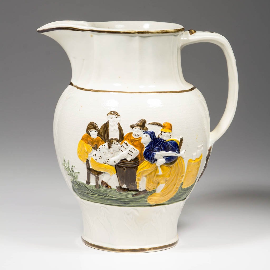 ENGLISH STAFFORDSHIRE POTTERY PEARLWARE MOLDED PITCHER: ENGLISH STAFFORDSHIRE POTTERY PEARLWARE MOLDED PITCHER, of baluster form, the wide strap handle with foliate lower terminate, with applied relief of peasants drinking to one side and of village musici