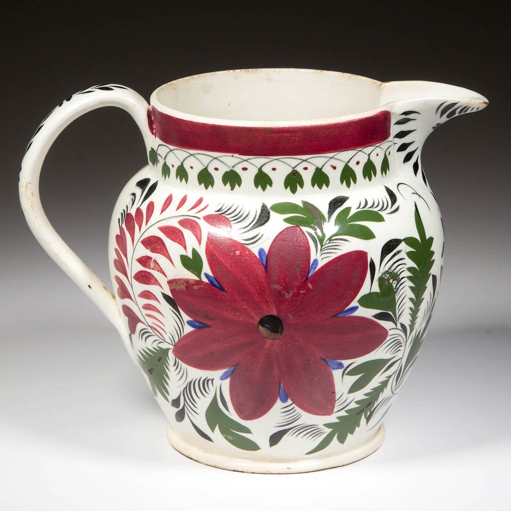 ENGLISH STAFFORDSHIRE POTTERY PEARLWARE PITCHER: ENGLISH STAFFORDSHIRE POTTERY PEARLWARE PITCHER, of baluster form, with wide C-form handle, painted with large stylized Aster flowers, foliage and feathering in red, green, black and blue. Unmarked. C