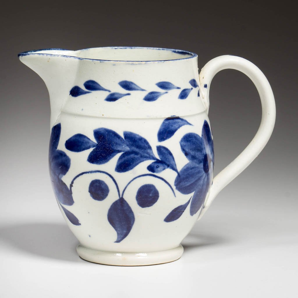 ENGLISH STAFFORDSHIRE POTTERY PEARLWARE SMALL CIDER JUG: ENGLISH STAFFORDSHIRE POTTERY PEARLWARE SMALL CIDER JUG OR PITCHER, of baluster form with simple handle, painted with blue slip narrow band over a lateral band of leaves, large stylized flowerheads an